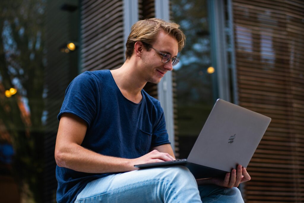 pexels photo 1438081 1438081 A young man sitting outdoors in Leiden, Netherlands, working on a laptop.